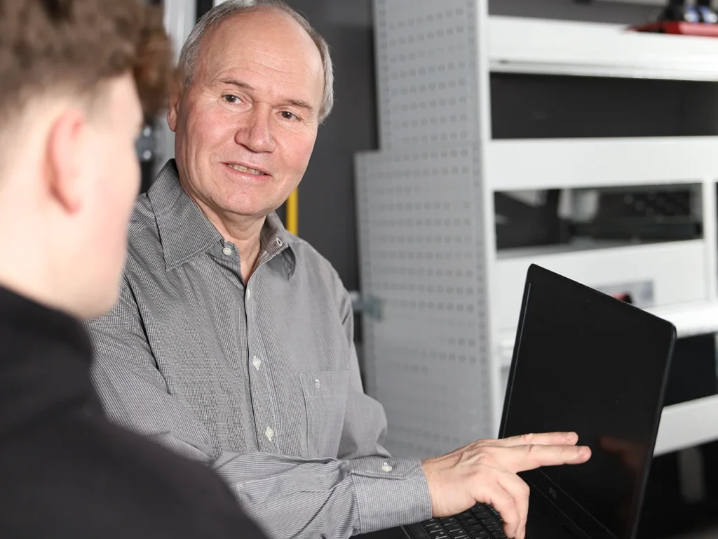 Geschäftsführer Andreas Handschug zeigt am Notebook etwas über die Fahrzeugeinrichtung